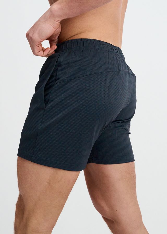 Back view of dark grey textured mesh gym shorts on a white background.