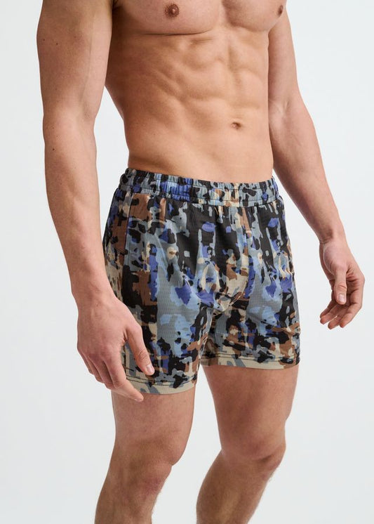 Cement and sand abstract printed mesh gym shorts on a torso.