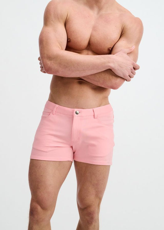 A person wearing petal-pink stretch knit shorts with belt loops and a front button closure against a white background.