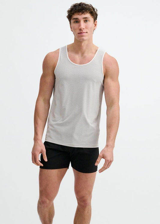A person wearing a white textured mesh tank top and black shorts against a plain white background.