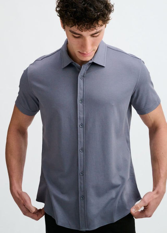 A person wearing a short-sleeve button-down stretch knit shirt in gravel grey.