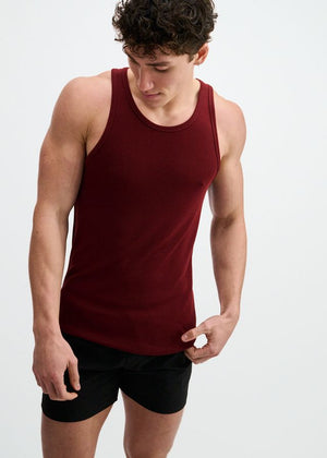 A person wearing a dark red, ribbed modal tank top and black shorts.