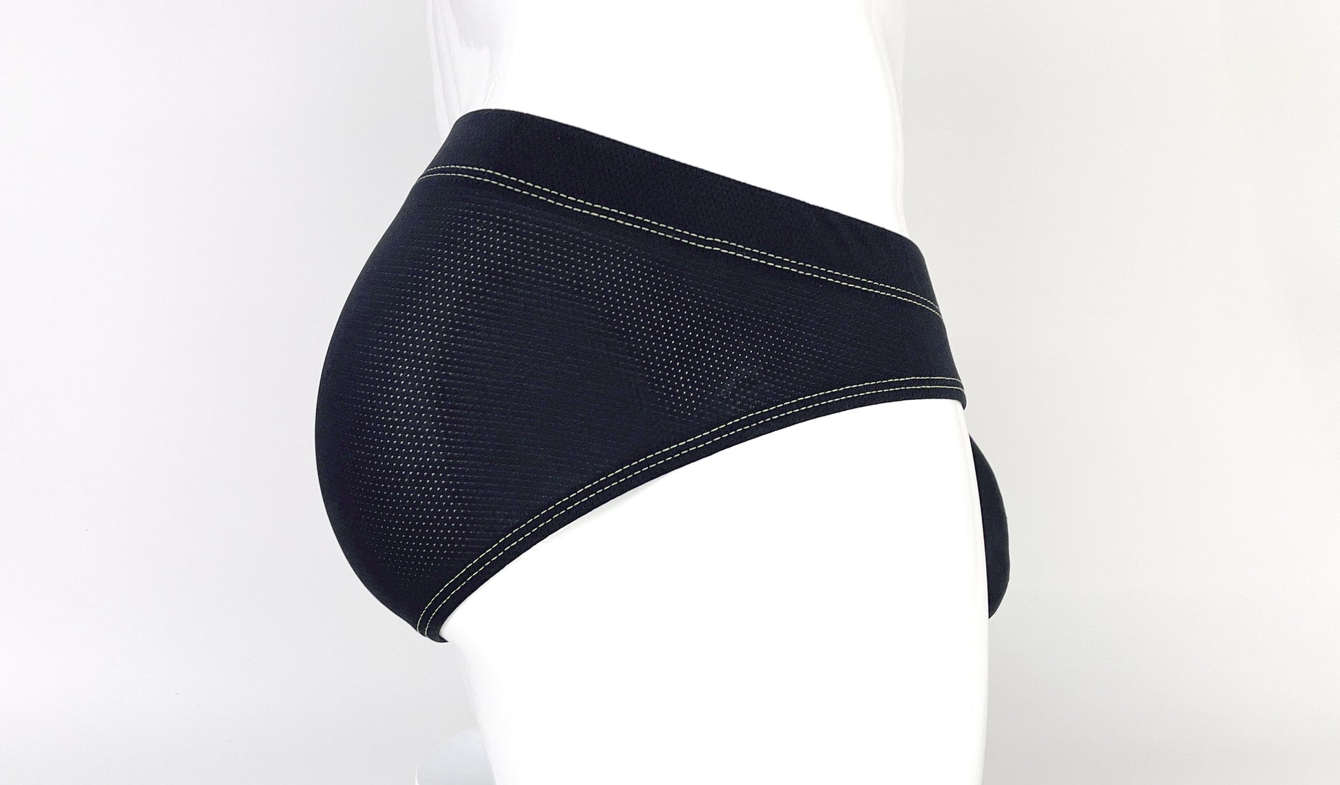 Side view of black, perforated mesh pouch brief featuring contrasting yellow stitching on a mannequin.