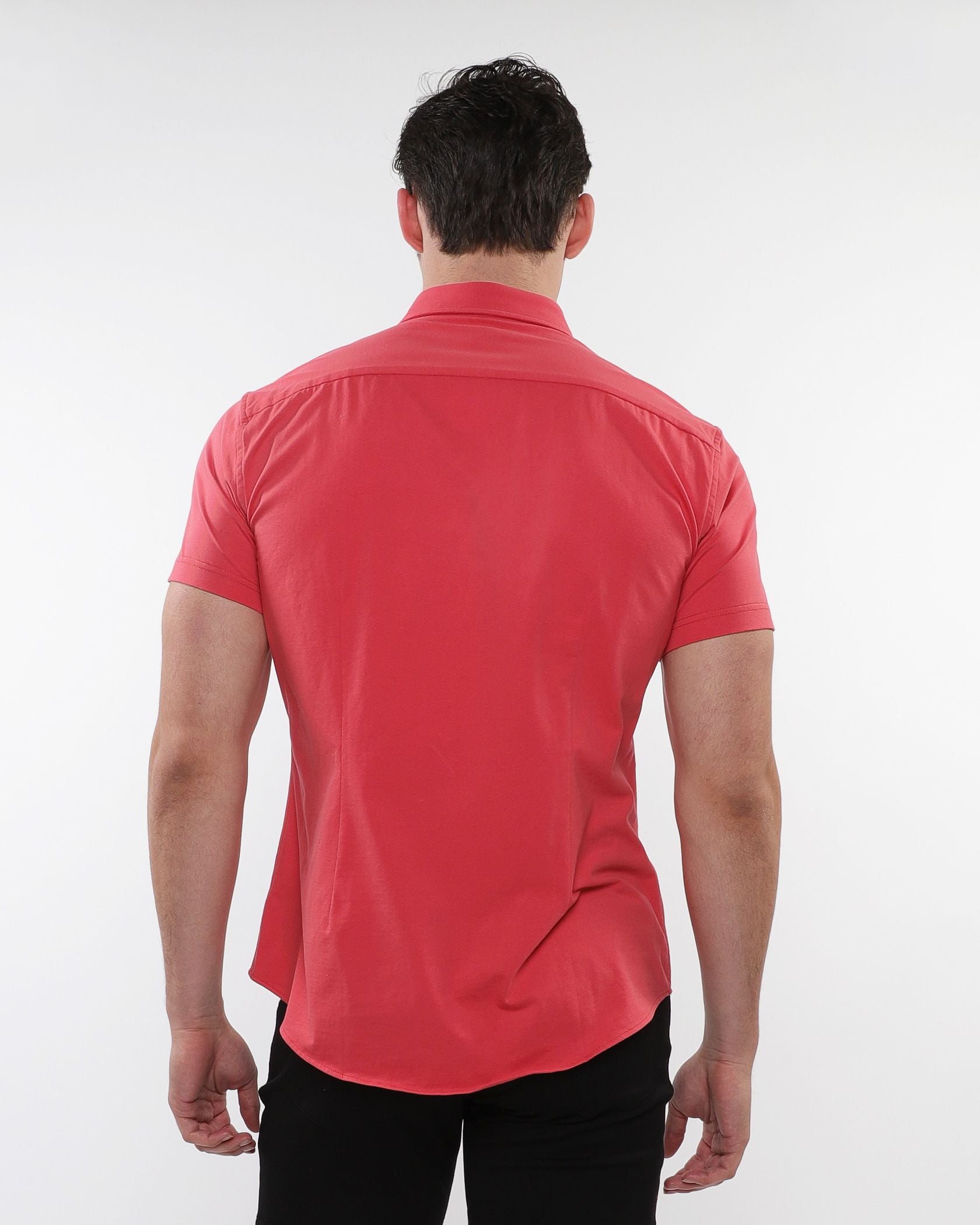 A man wearing a vibrant coral stretch knit short-sleeved dress shirt with tailored fit and subtle stitching details