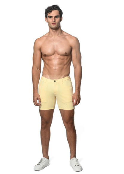 A pair of pale yellow stretch knit shorts with a single button closure and belt loops in a form-fitting style