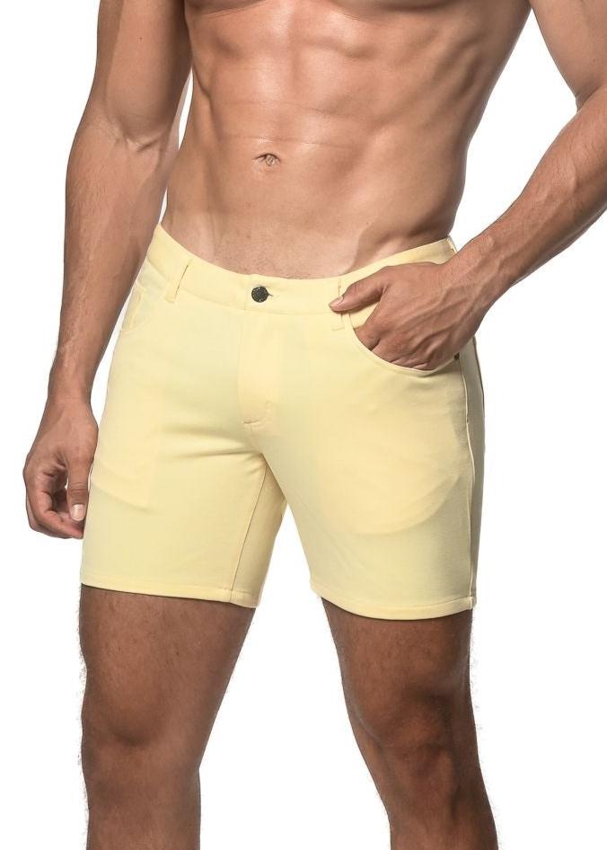 A pair of pale yellow stretch knit shorts with a classic button closure and side pockets in a form-fitting design