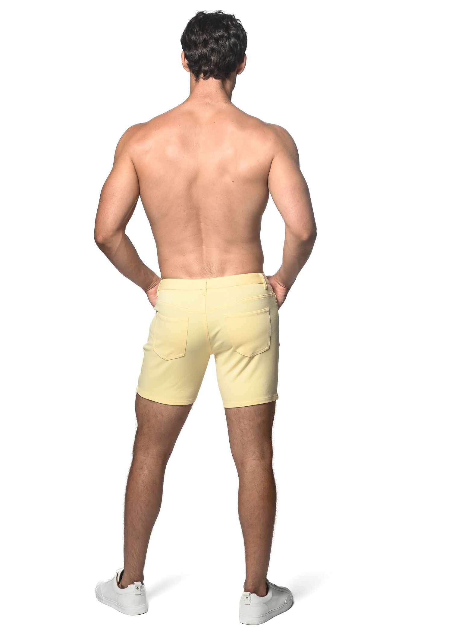 Light yellow stretch knit shorts with a tailored fit and two back pockets shown from the back side