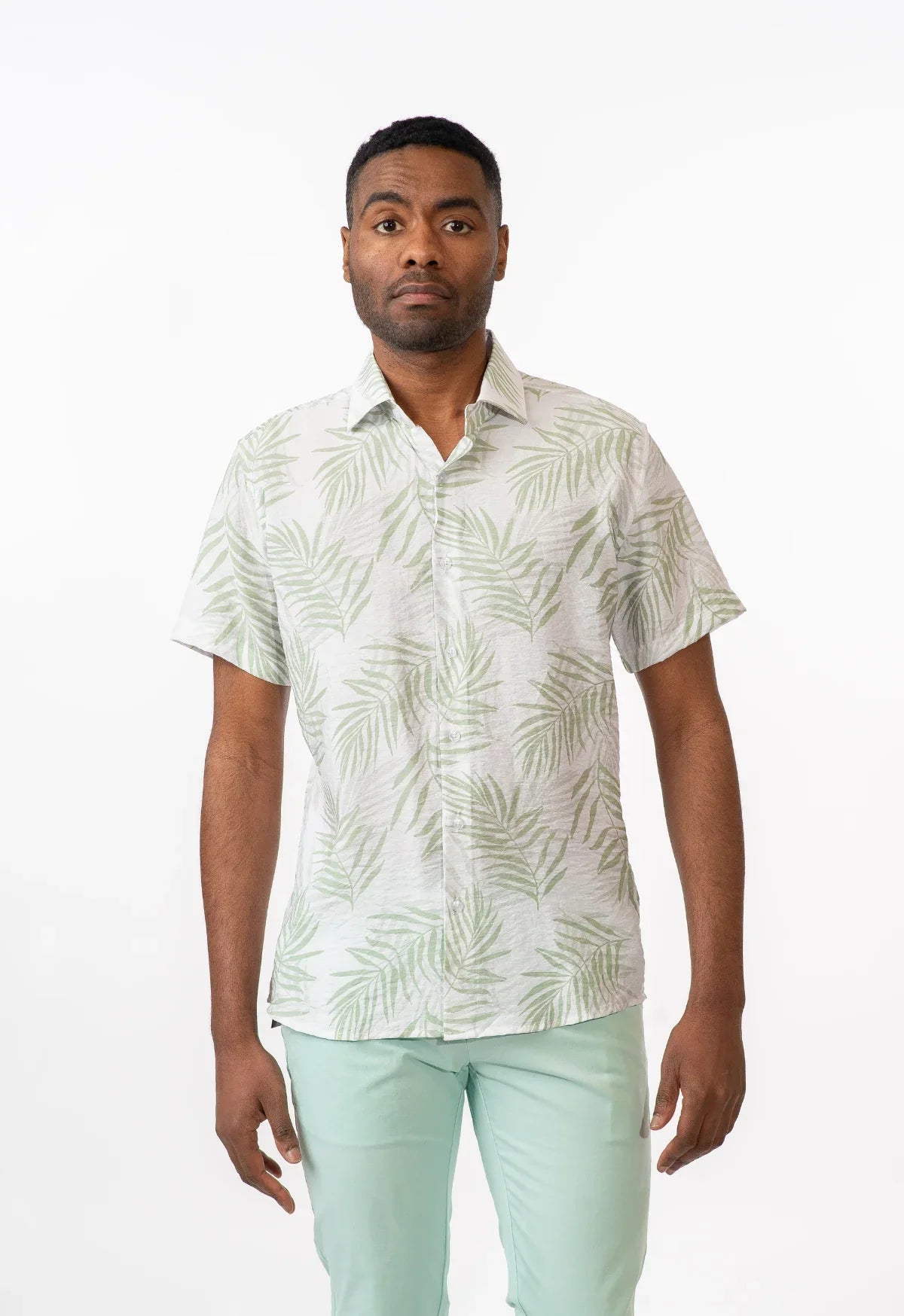 A man wearing a summer rain s s shirt with light green palm leaf pattern on off-white short-sleeved button-up fabric