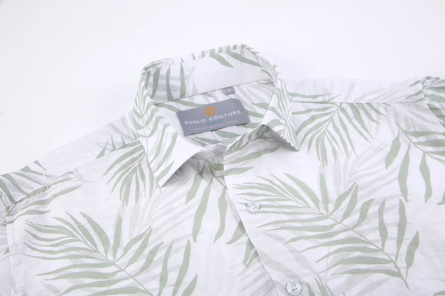 A white button-down summer rain shirt with a subtle green palm leaf pattern and suslo couture label at the collar