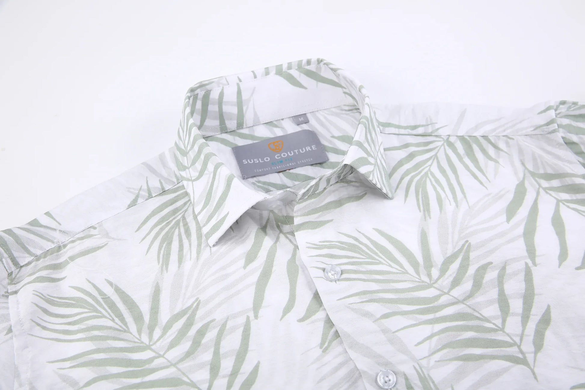 A white button-down summer rain shirt with a subtle green palm leaf pattern and suslo couture label at the collar