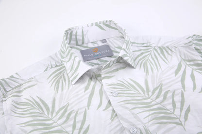 A white button-down summer rain shirt with a subtle green palm leaf pattern and suslo couture label at the collar