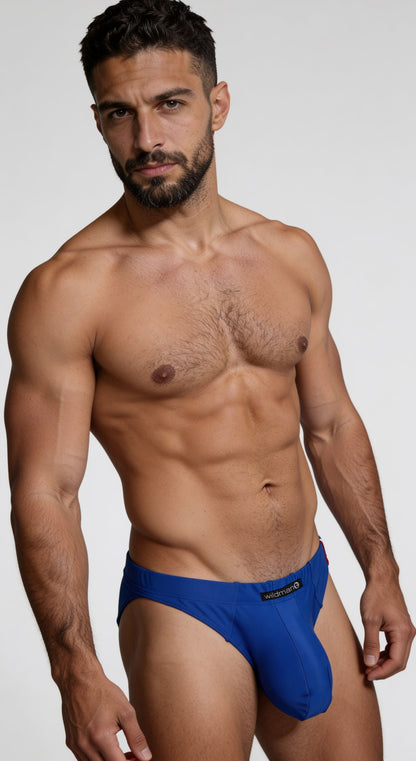 Man wearing a royal blue WildmanT Big Boy pouch swim brief with a prominent contoured front pouch and logo tag.