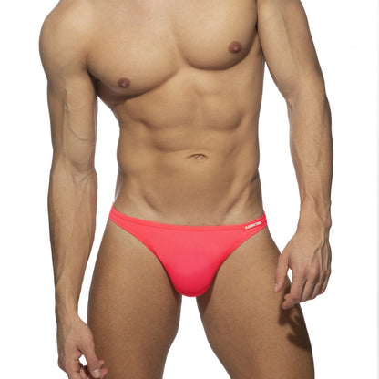 Bright pink form-fitting swimwear g-string swim trunks with a subtle brand logo on the waistband front side