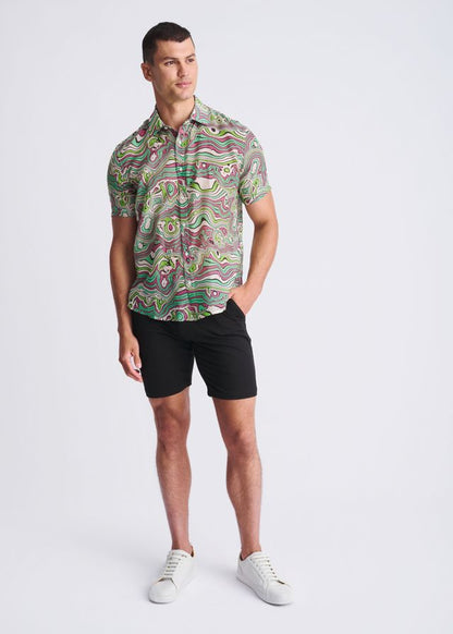 A man wearing a swirls lightweight cotton silk short-sleeved shirt with green pink and beige abstract patterns