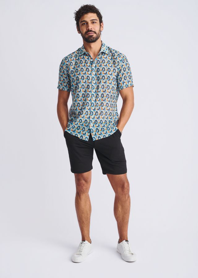 A man wearing a swirls lightweight cotton silk short-sleeved shirt with blue teal and beige circular patterns