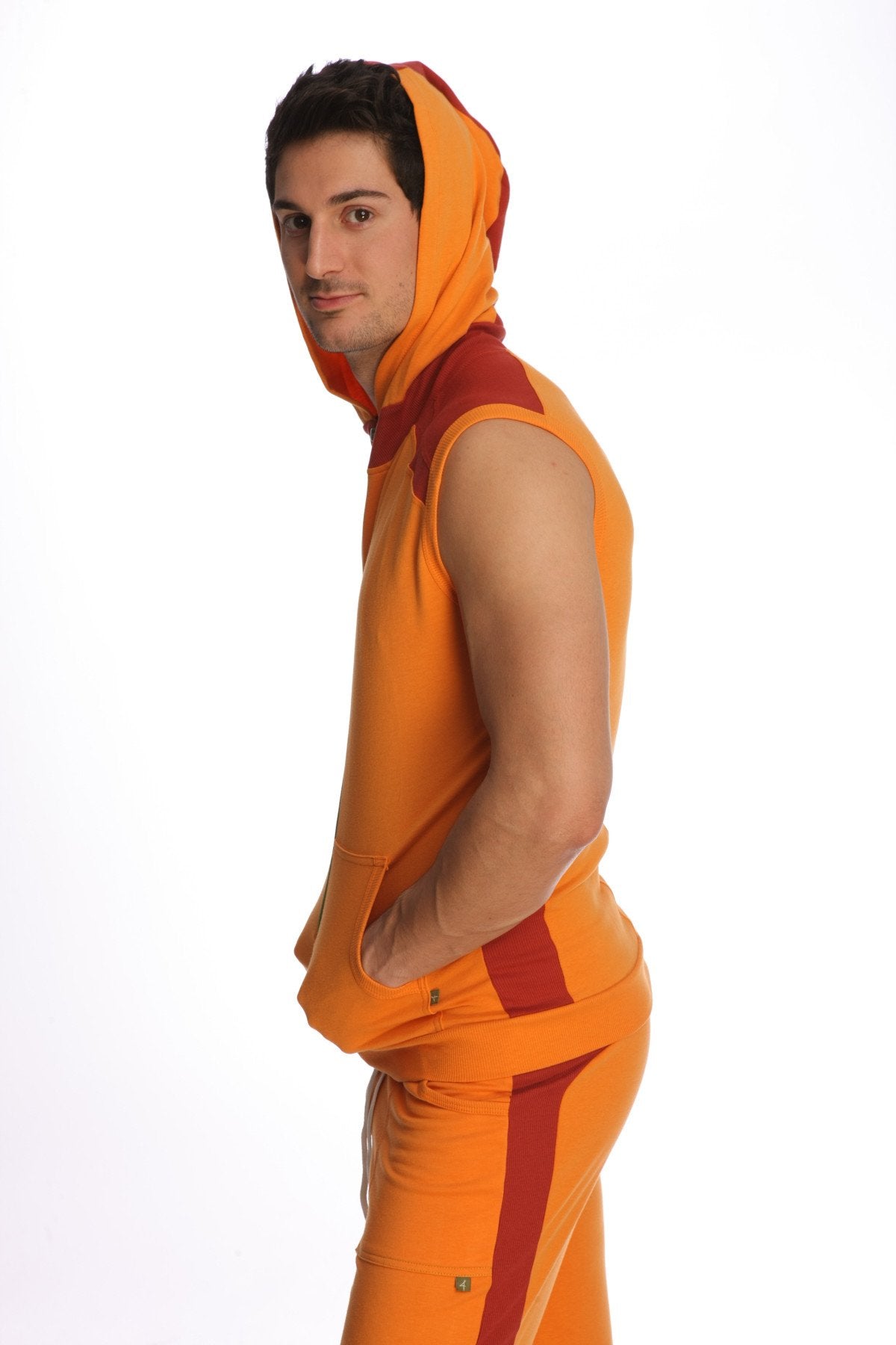 Sleeveless yoga hoodie in sun orange with bold orange and red color blocking and matching pants shown from the back