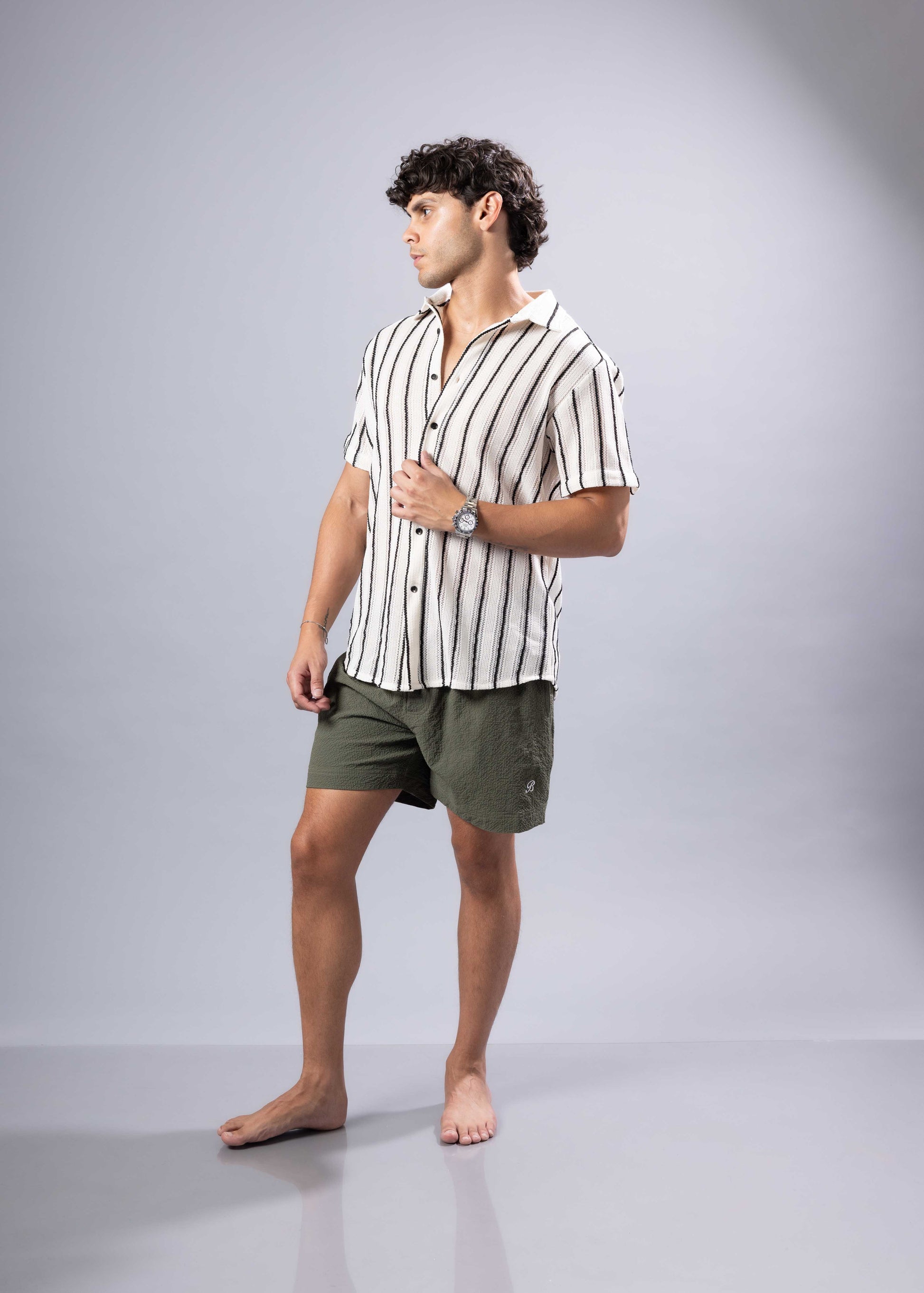 A man wearing a texture knit short-sleeved shirt with vertical black and white stripes in a casual style