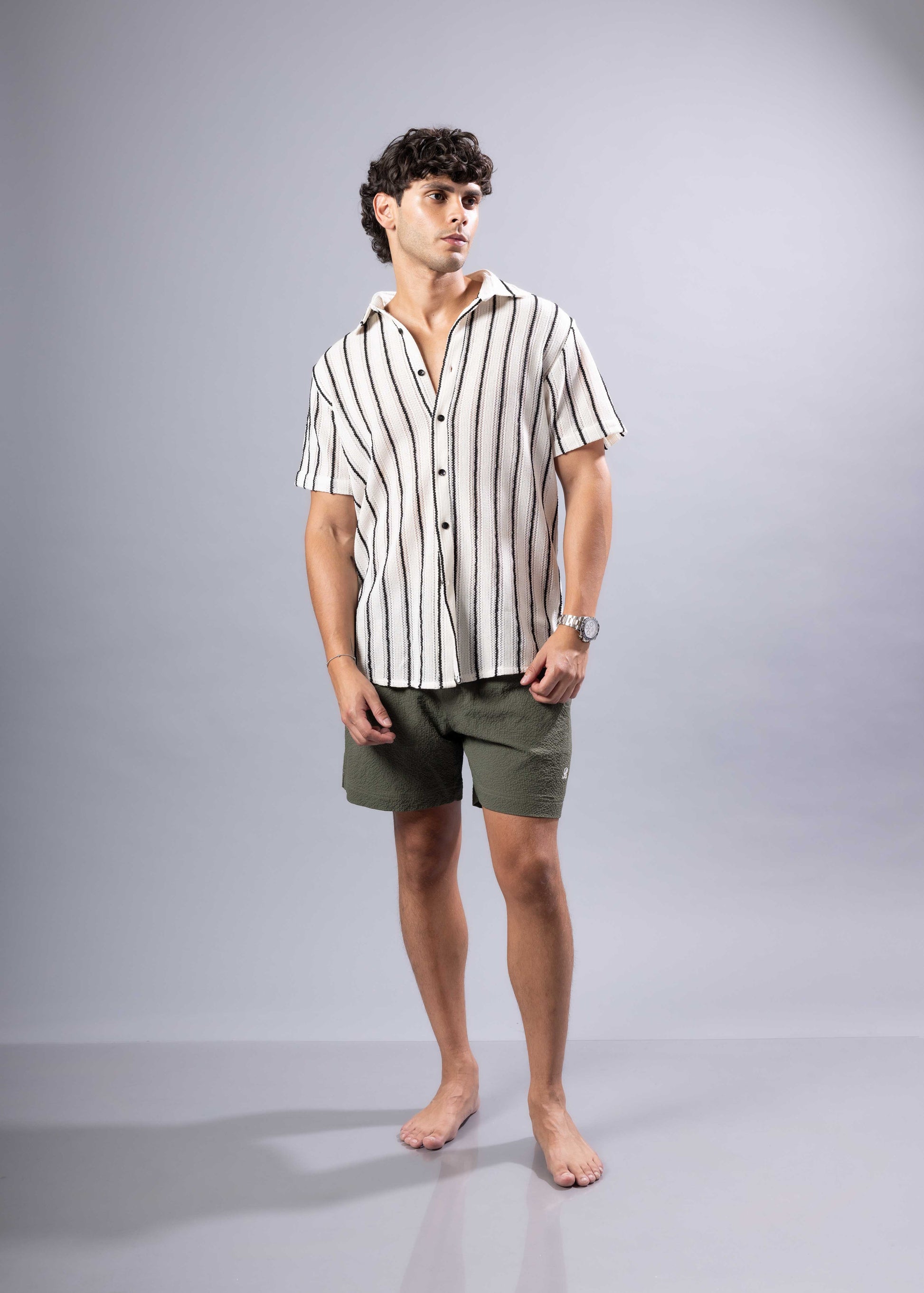 A man wearing a texture knit s s shirt with vertical black and off white stripes in short sleeves