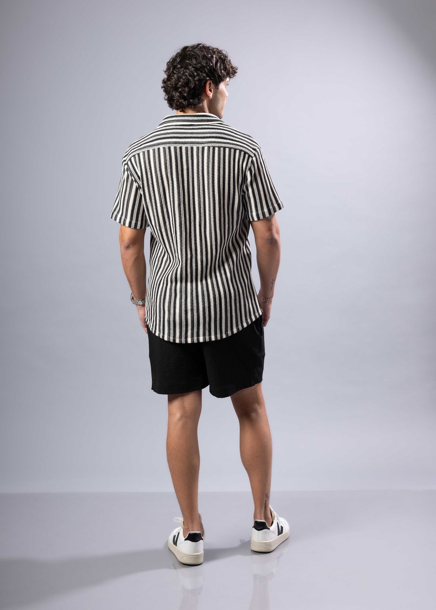 A man wearing a black and white vertically striped texture knit short-sleeved shirt for casual wear