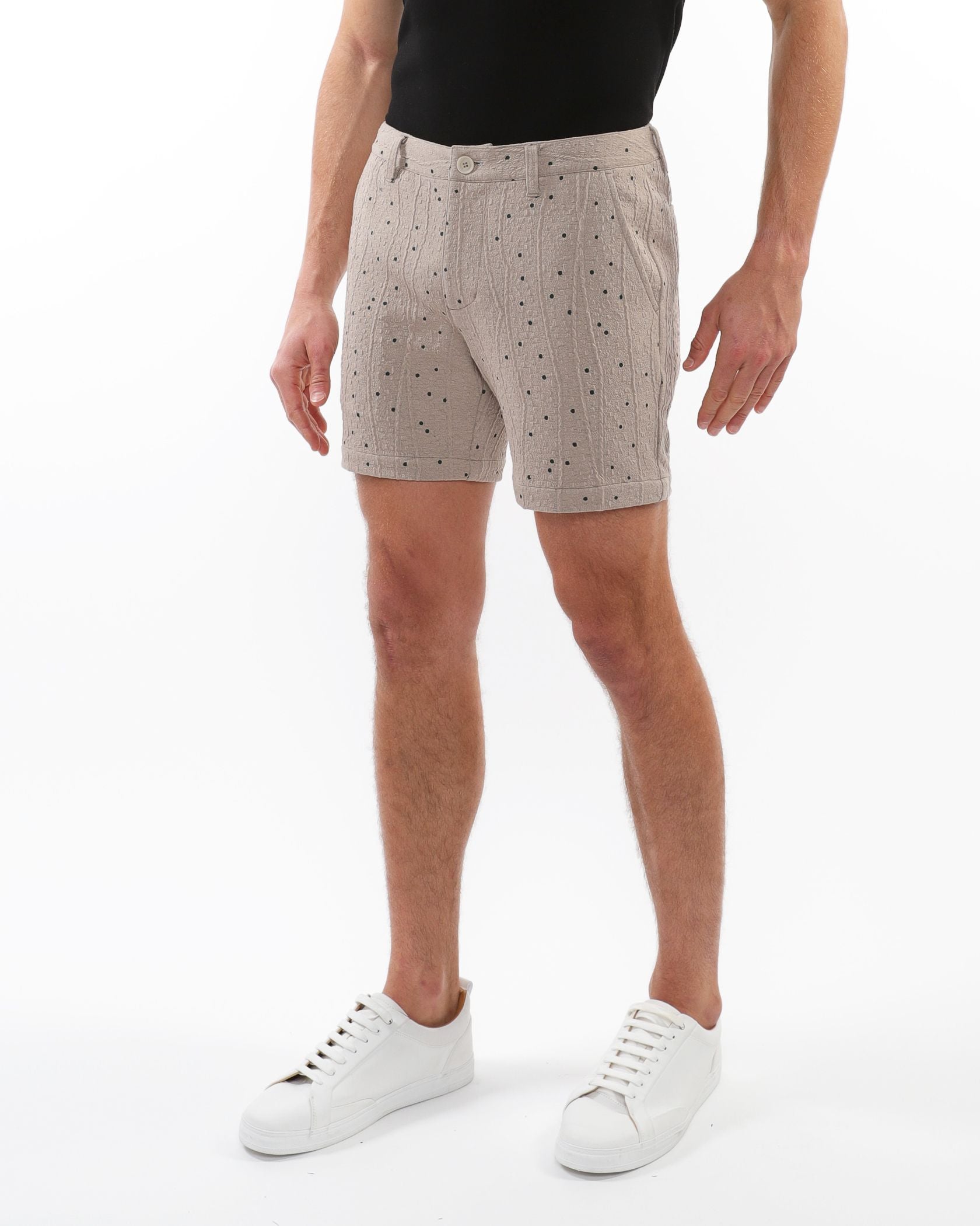Beige textured jacquard stretch chino shorts with a subtle black polka dot pattern and woven fabric detail