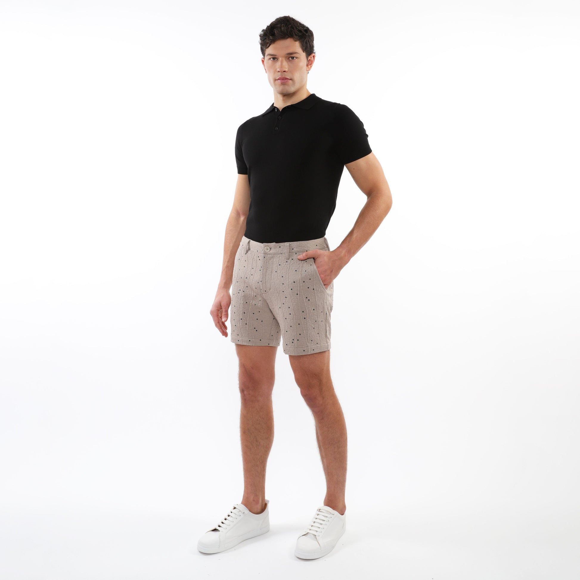 Beige textured jacquard stretch chino shorts with subtle dark dot pattern worn by a model in casual summer attire