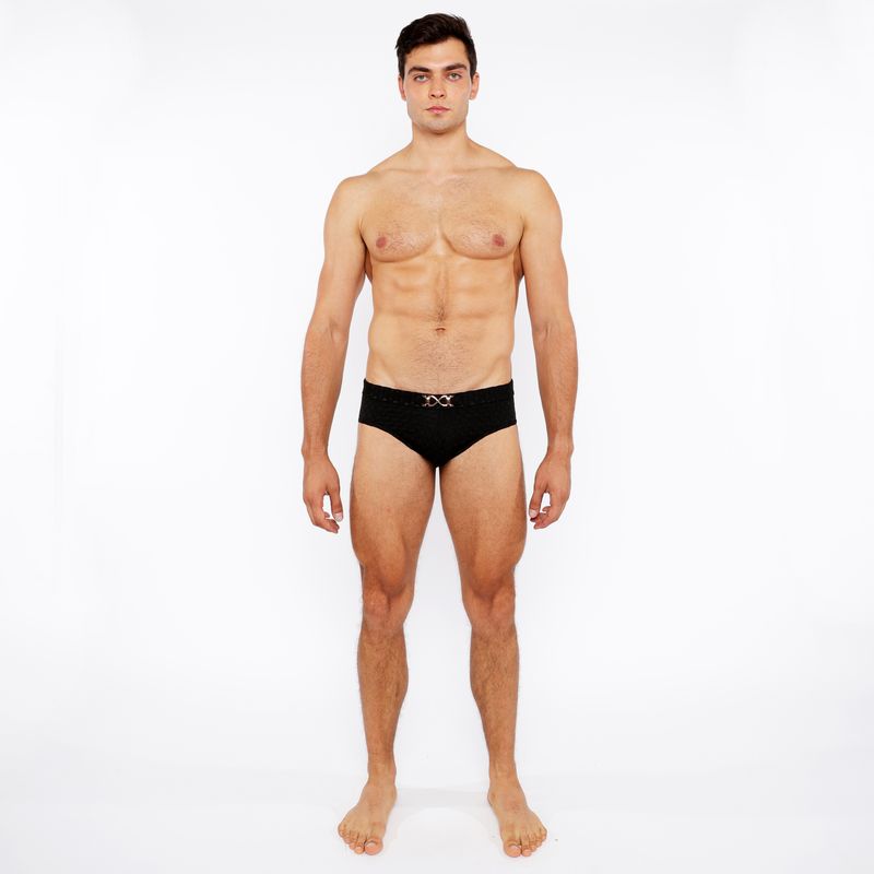 Black textured swim brief with front buckle and silver metallic x-shaped logo on waistband for swimming use