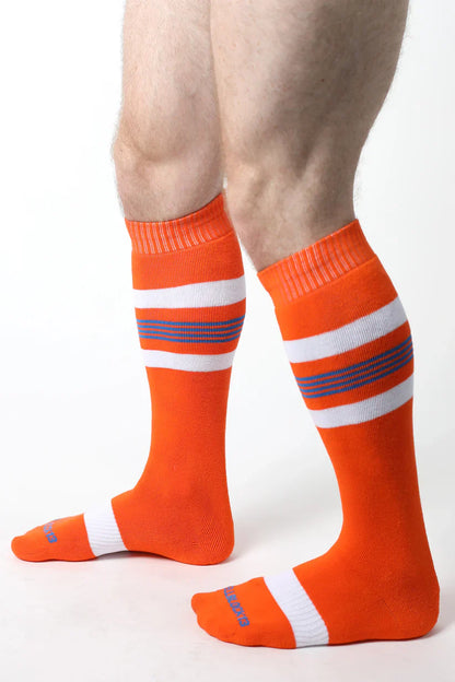 Tight end knee high socks in bright orange with white and purple stripes featuring ribbed cuff and toe design