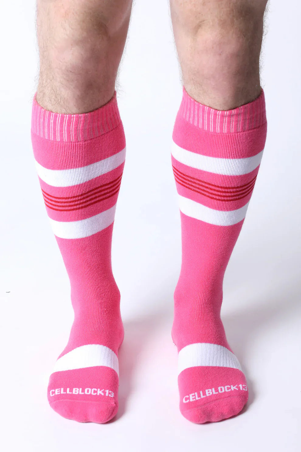 Bright pink tight end knee high socks with white and red stripes featuring cellblock13 logo on the toe