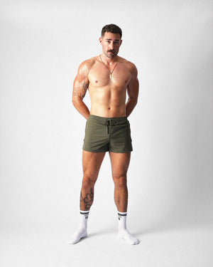 Front view of army green gym shorts with a drawstring waist, worn with white socks.