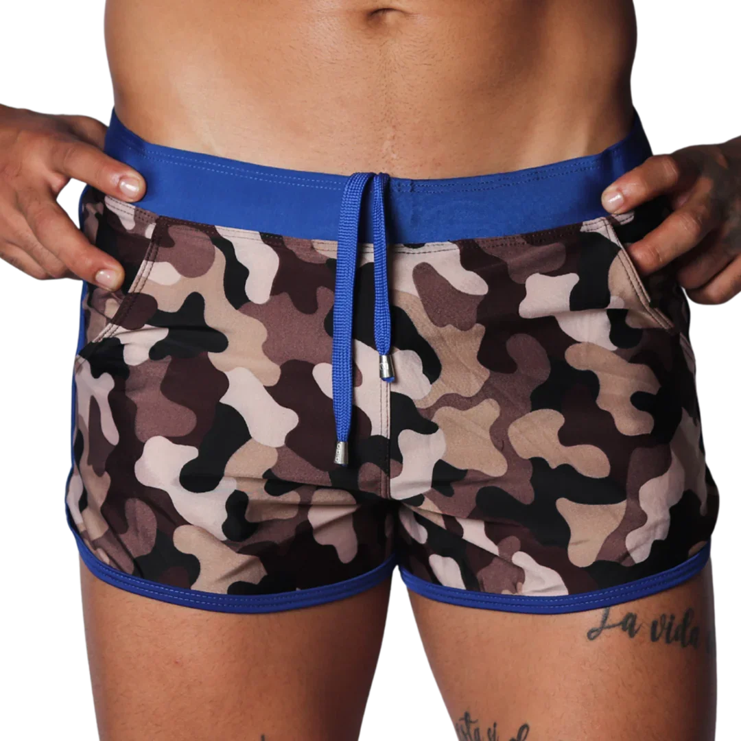 Camo print swim shorts with a blue elastic waistband, matching drawstring, and blue trim detail on a black background.