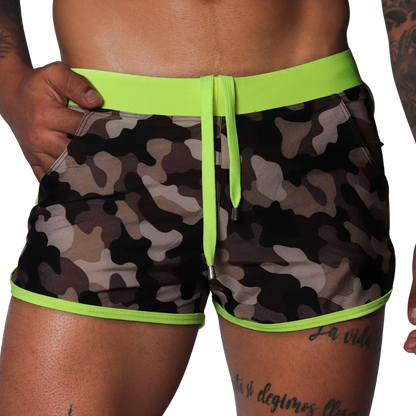 Short camouflage swim trunks with neon yellow elastic waistband, matching drawstring, and neon yellow piped trim.