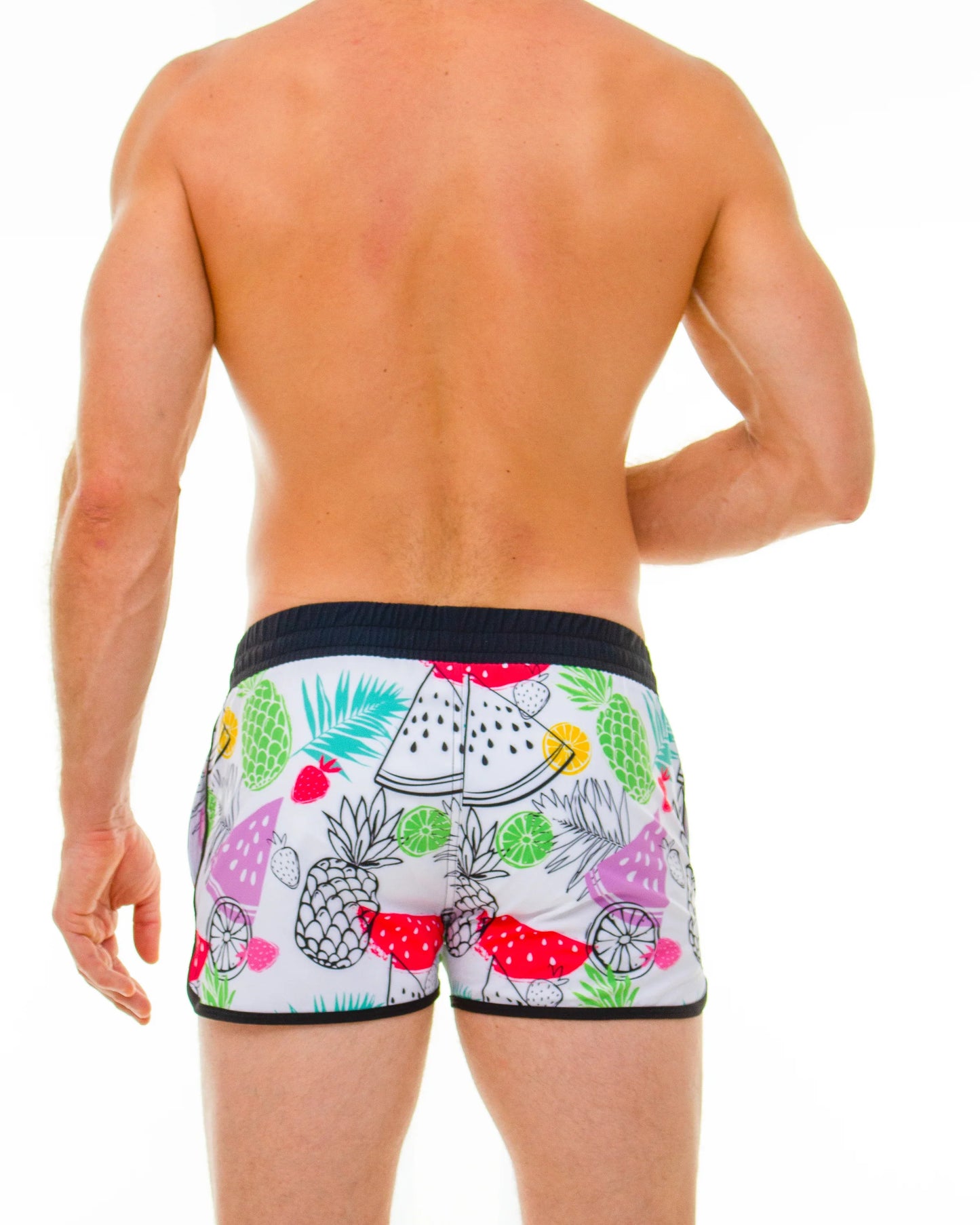 White swim trunks with a vibrant tropical fruit pattern of pineapples watermelon and limes in bright colors