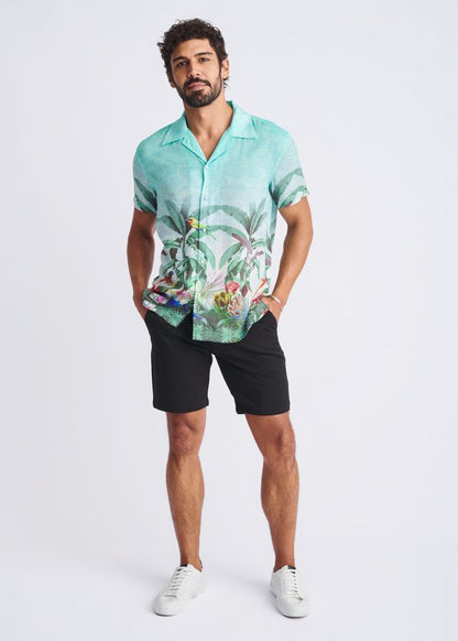 A men’s short-sleeved turquoise modal shirt with a detailed tropical print featuring foliage and colorful birds