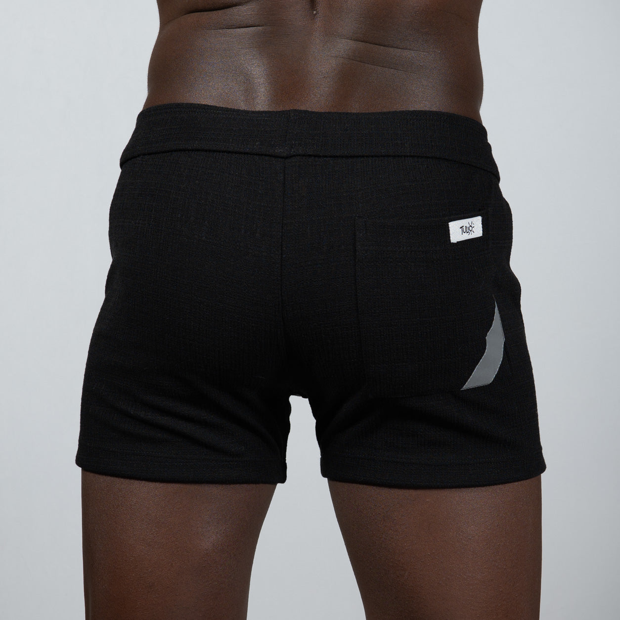 Black tulio linen texture shorts with ribbed waistband and silver reflective side stripe for athletic use