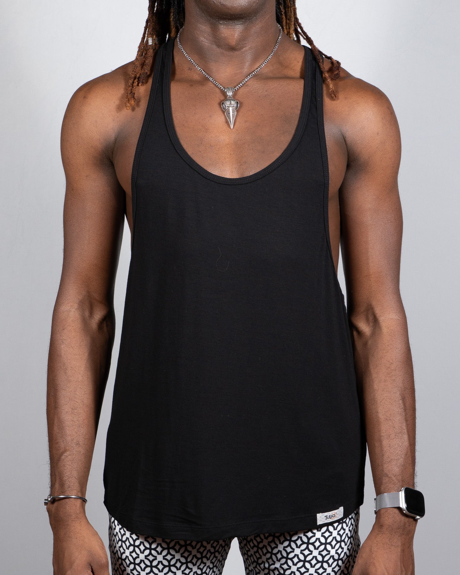 Black tulio racerback tank top with minimalist design and small brand tag at bottom hem in 4 colors available