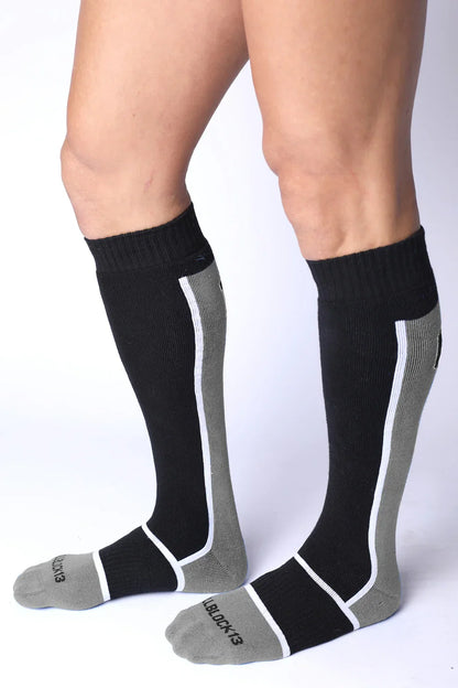 Knee-high athletic socks in black, grey, and white with ribbed cuffs and contrasting side stripes.