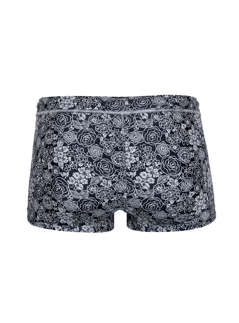 Black briefs tartarus swim trunk with intricate white floral pattern on fabric for swimwear use