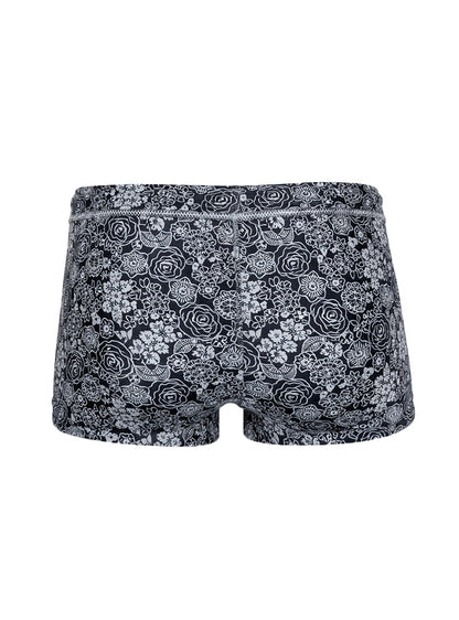 Black briefs tartarus swim trunk with intricate white floral pattern on fabric for swimwear use
