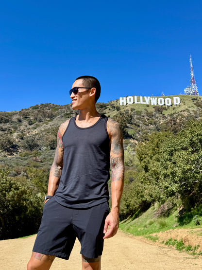 A man wears the perfect tank black carbon sleeveless top and shorts on a dirt path with the Hollywood sign background