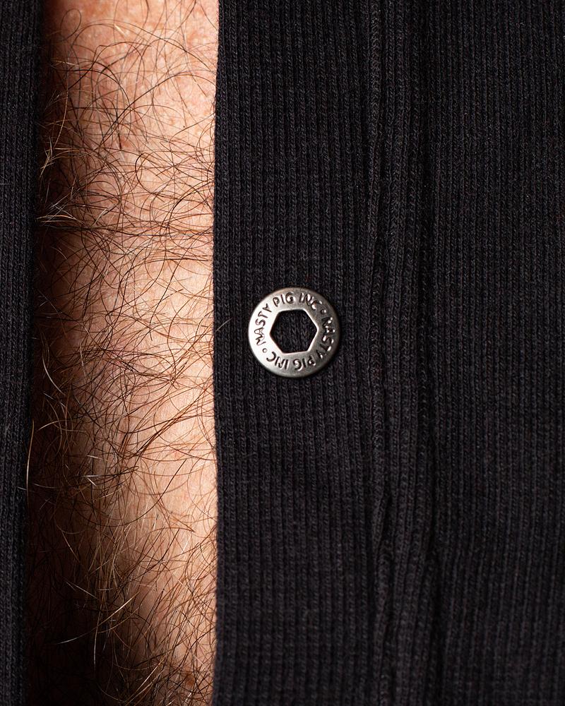 Union suit featuring a silver-toned hexagonal snap button engraved with musty pig inc on black ribbed fabric