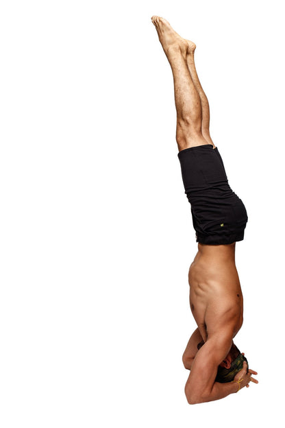A man performing a headstand wearing black Urban Tactical at Home dress shorts made for comfort and flexibility