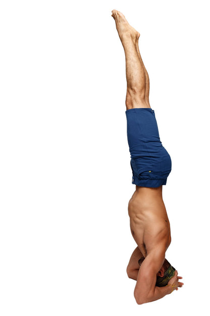 A muscular man performing a headstand wearing royal blue urban tactical at home dress shorts designed for comfort and durability