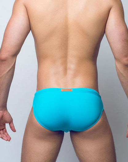 Bright turquoise v10 core bikini swim trunks with a small orange brand tag at the waistband for swimming use
