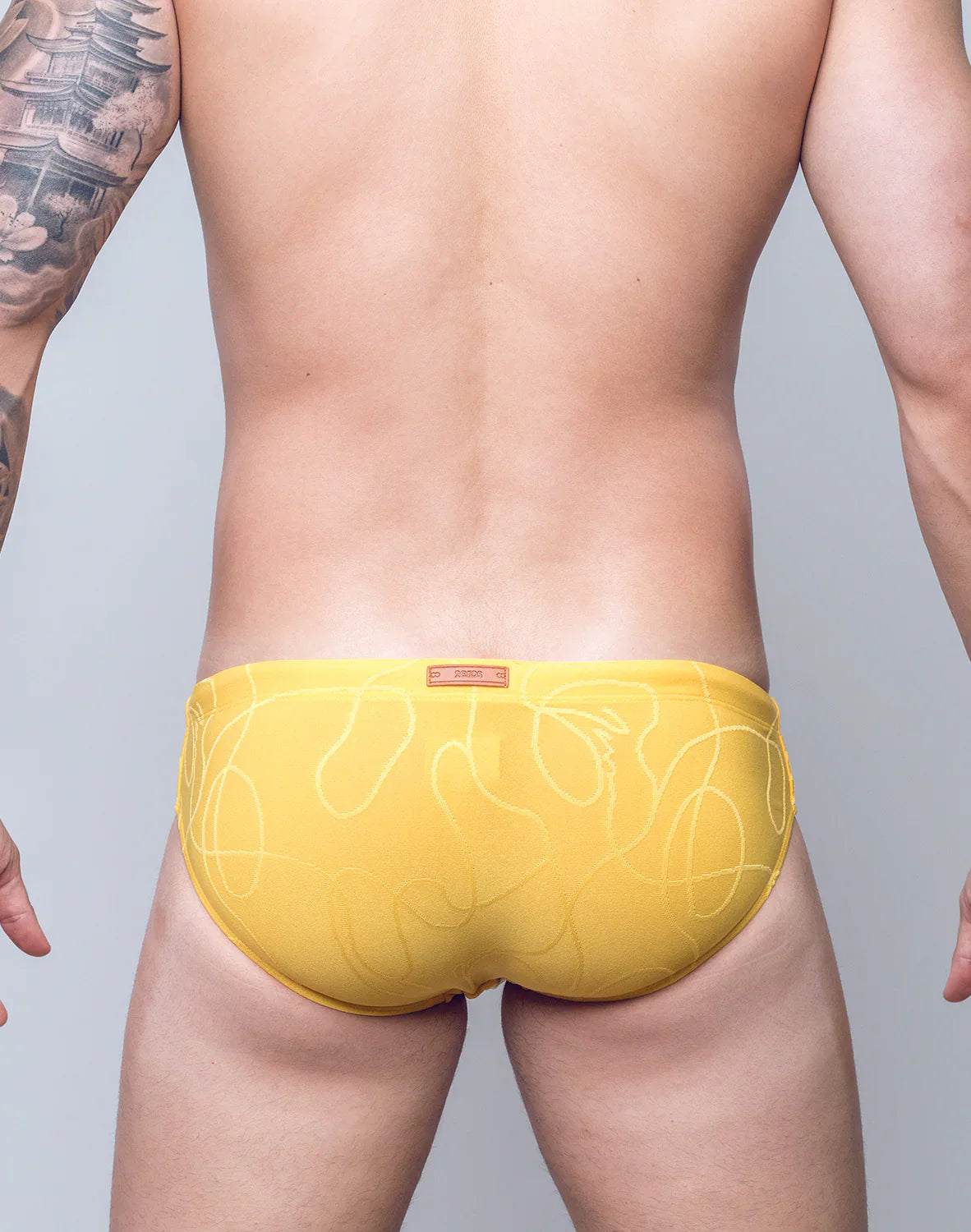 Yellow V10 ripple textured swim brief with subtle white abstract line pattern designed for swimwear use