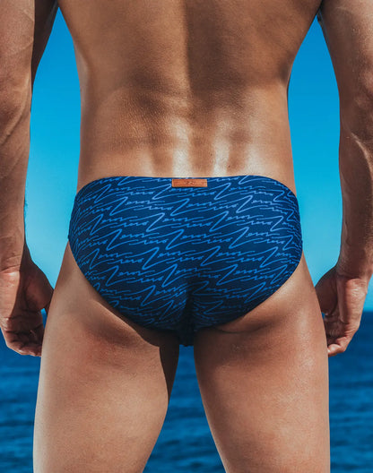 Blue swim trunks v20 signature print swim brief with light blue abstract line pattern and orange brand tag at waistband