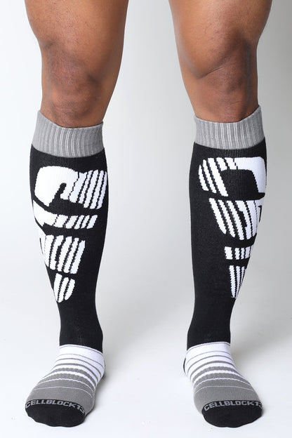 Black and white velocity 2.0 knee high compression socks with bold skull design on calf in back view