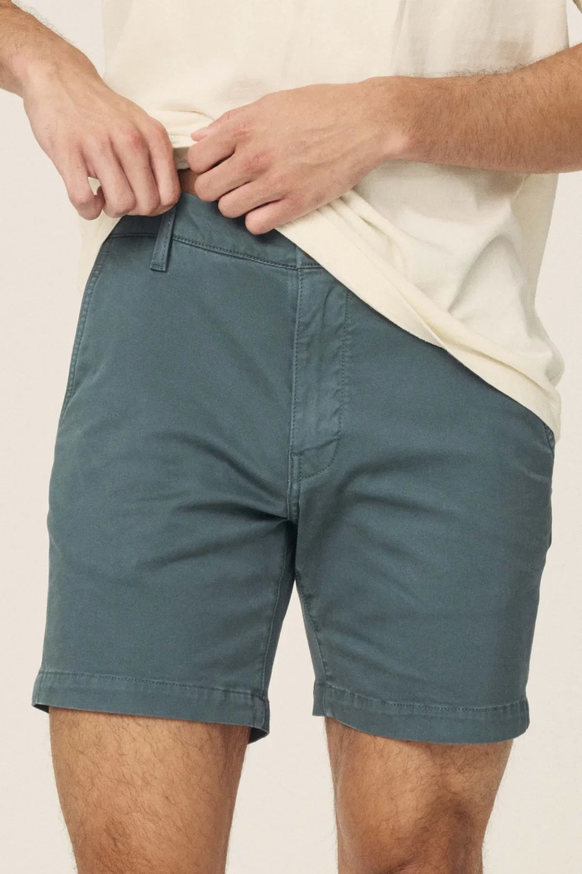 Teal-grey chino shorts with a zip fly and belt loops, paired with a cream-colored t-shirt.