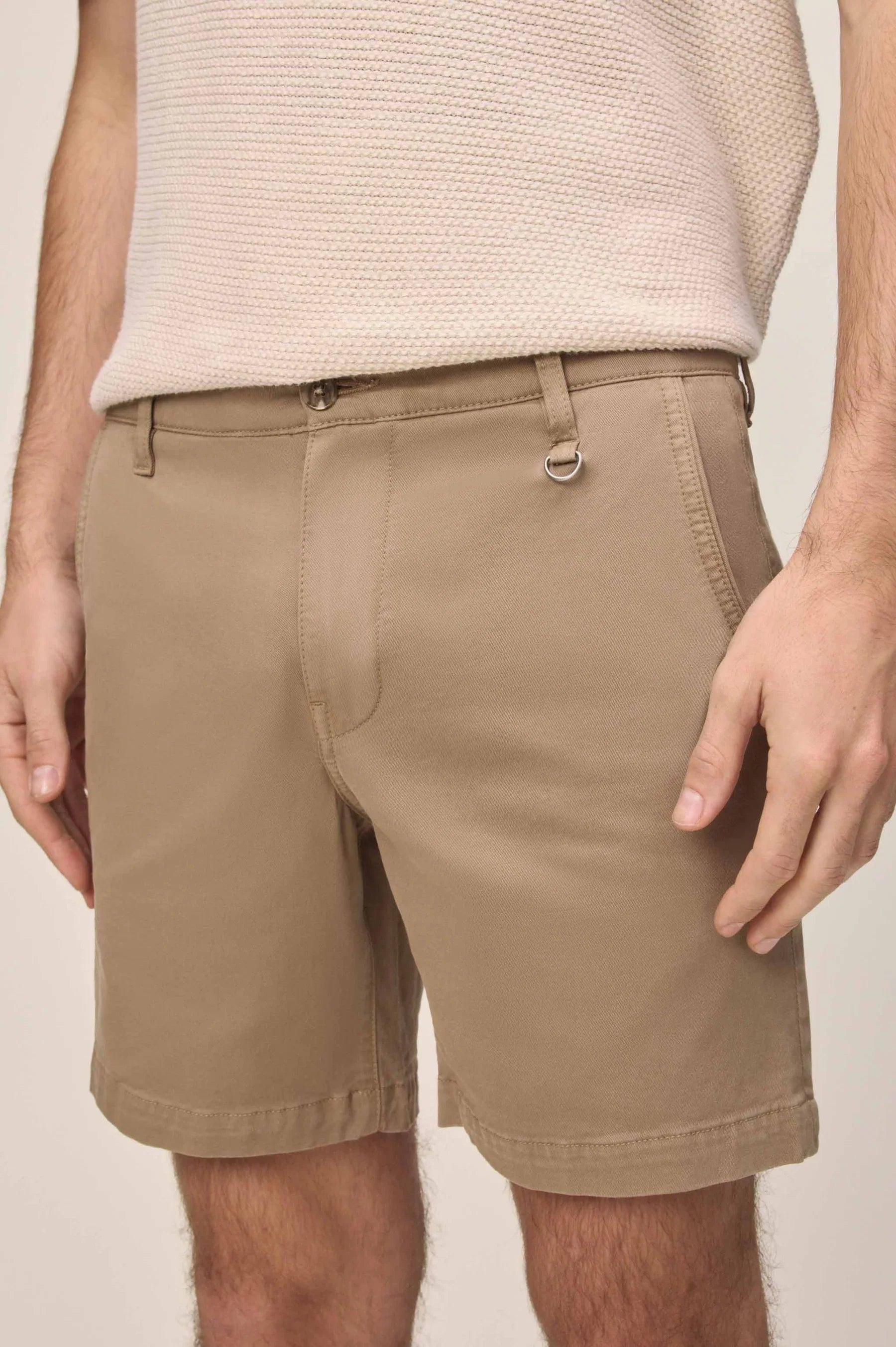 Tan chino shorts with a metal D-ring on the front belt loop, paired with a beige knit shirt.