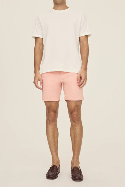 A person wearing a white t-shirt, pink chino shorts, and brown loafers.