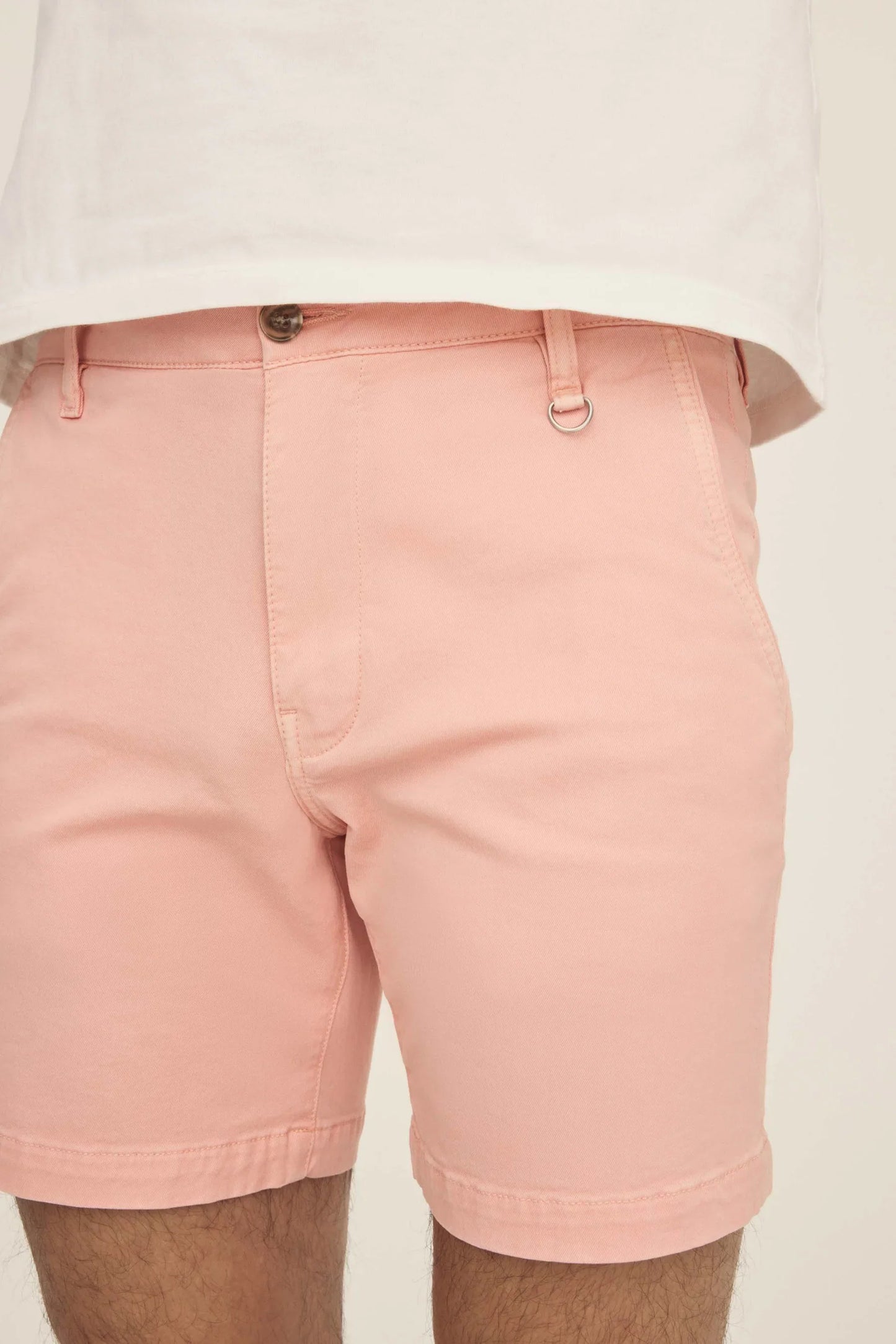 Close-up of pink chino shorts with a metal D-ring on the waistband.